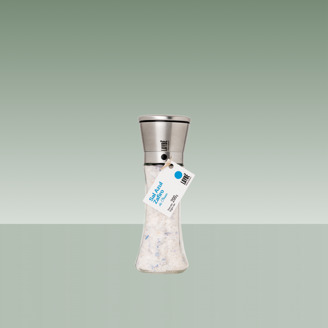 Molinillo de sal marina azul en botella de vidrio transparente con mecanismo metálico y etiqueta colgante.