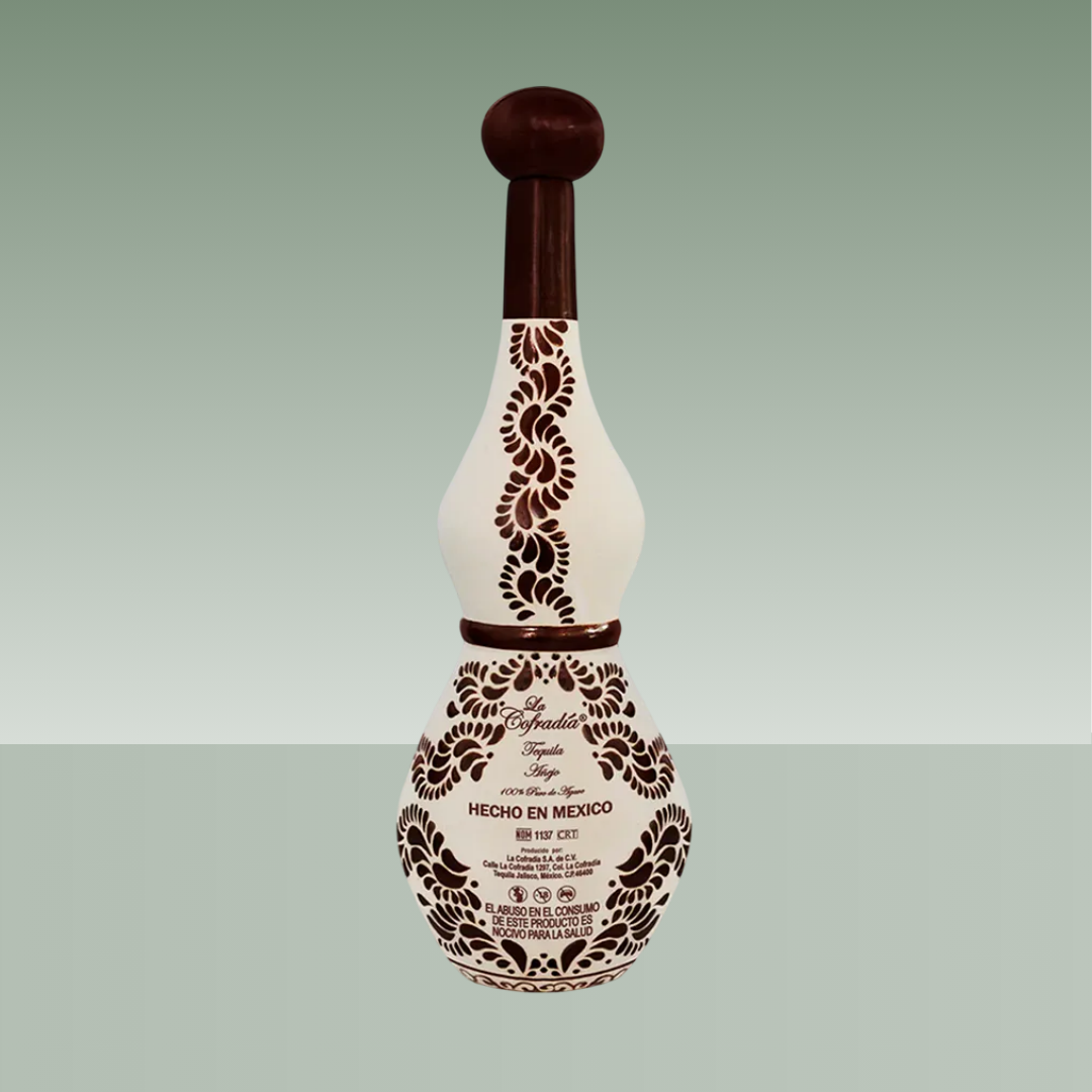 Botella de tequila de cerámica artesanal pintada a mano en tonos crema y marrón, con motivos florales y de agave, cuello alargado y tapón cerámico oscuro.
