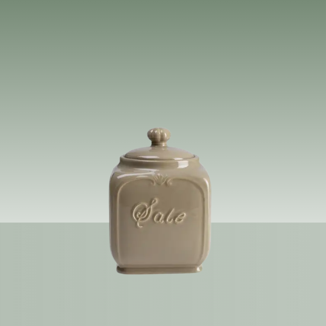 Salero de cerámica beige con tapa, diseño clásico de inspiración vintage y la palabra “Sale” en relieve, acabado brillante presentado sobre fondo neutro.