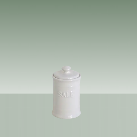 Salero de cerámica blanca con tapa, diseño clásico y acabado brillante, con la palabra “SAL” en relieve, presentado sobre fondo neutro.