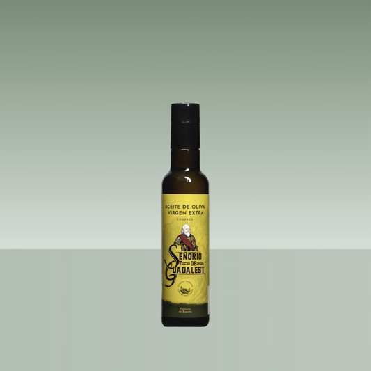 Botella de aceite de oliva virgen extra Señorío de Guadalest coupage, envase de vidrio oscuro con etiqueta amarilla ilustrada y tapón negro, presentada sobre fondo neutro.