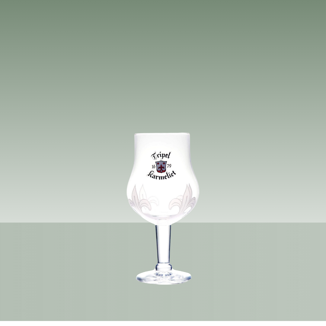 Copa de cerveza Tripel Karmeliet, de cristal transparente con cáliz ancho y tallo fino, serigrafiada con el logotipo de la marca, presentada sobre fondo neutro verde suave.