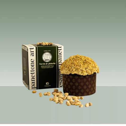 Panettone artesanal Turrón de pistacho de Raúl Asencio, con cobertura de pistacho triturado, presentado junto a su caja negra y verde, con pistachos enteros alrededor sobre fondo neutro.