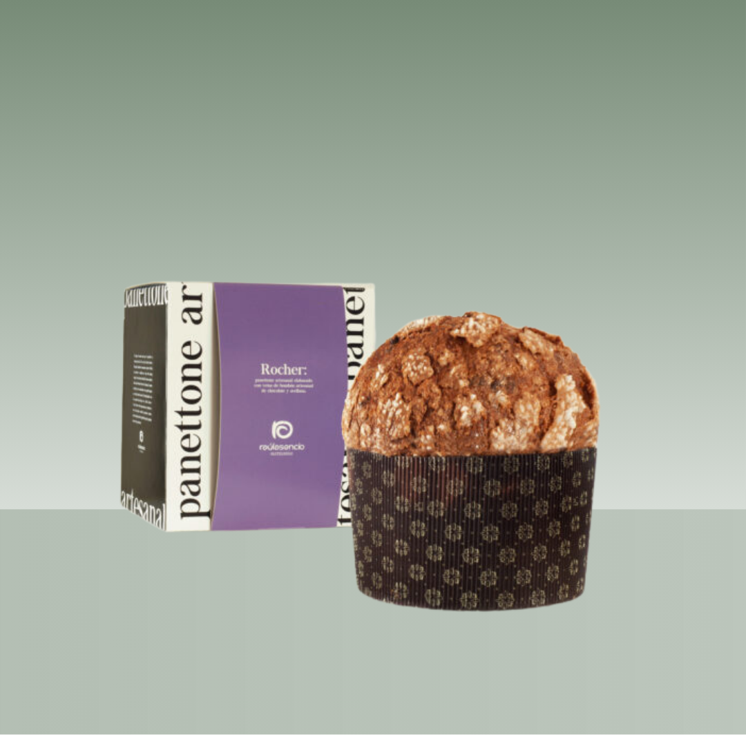 Panettone artesanal Rocher de Raúl Asencio, con cobertura crujiente y acabado rústico, presentado junto a su caja en tonos morado y negro sobre fondo neutro.