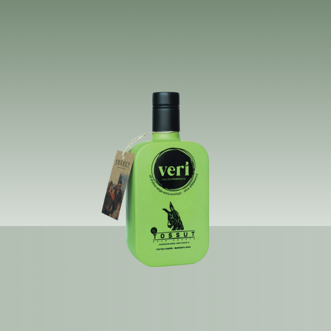 Botella de aceite de oliva virgen extra Tossut Veri, de color verde intenso, con envase plano de diseño moderno, tapón negro y etiqueta colgante, presentada sobre fondo neutro.