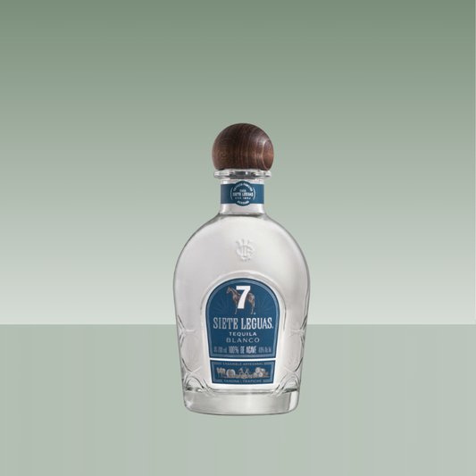 Botella de tequila Siete Leguas Blanco, de vidrio transparente con tapón de madera y etiqueta azul frontal.
