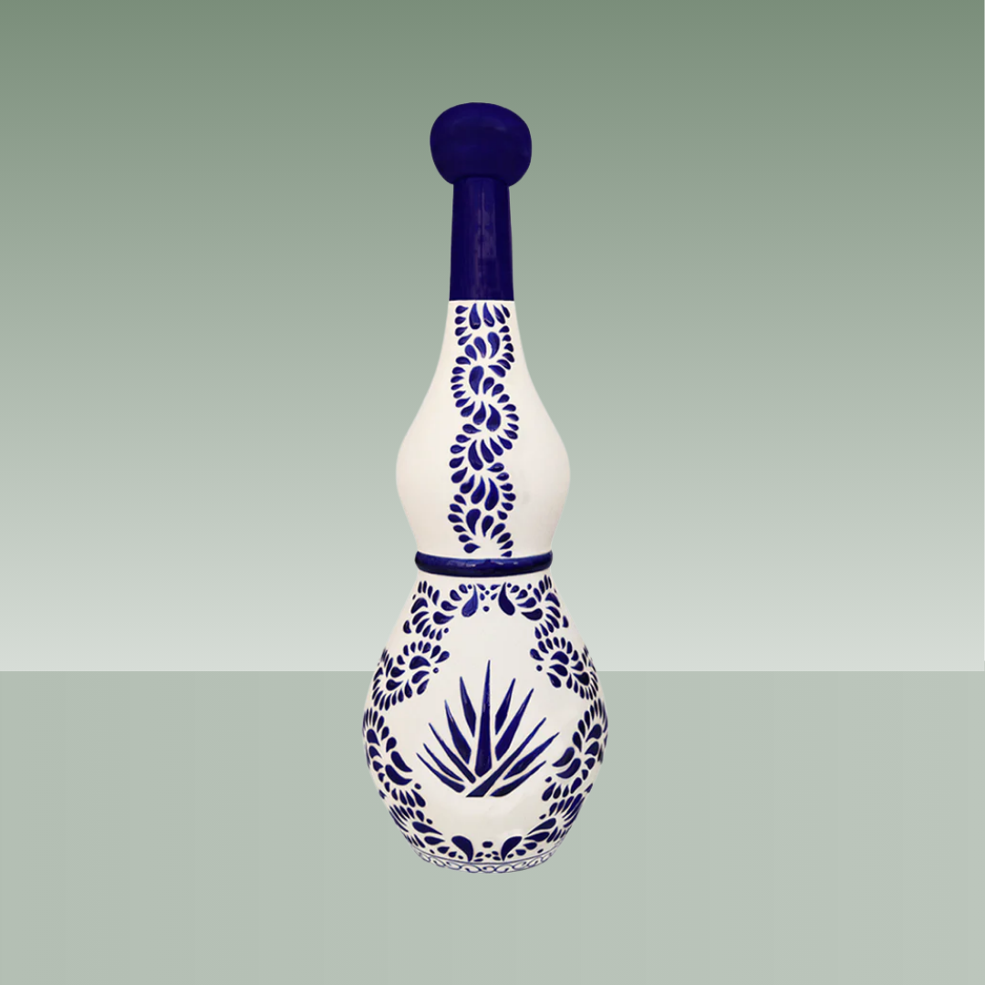 Botella artesanal de cerámica blanca con decoración azul cobalto, motivos vegetales y agave, tapón superior del mismo material.