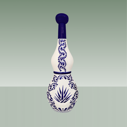 Botella artesanal de cerámica blanca con decoración azul cobalto, motivos vegetales y agave, tapón superior del mismo material.