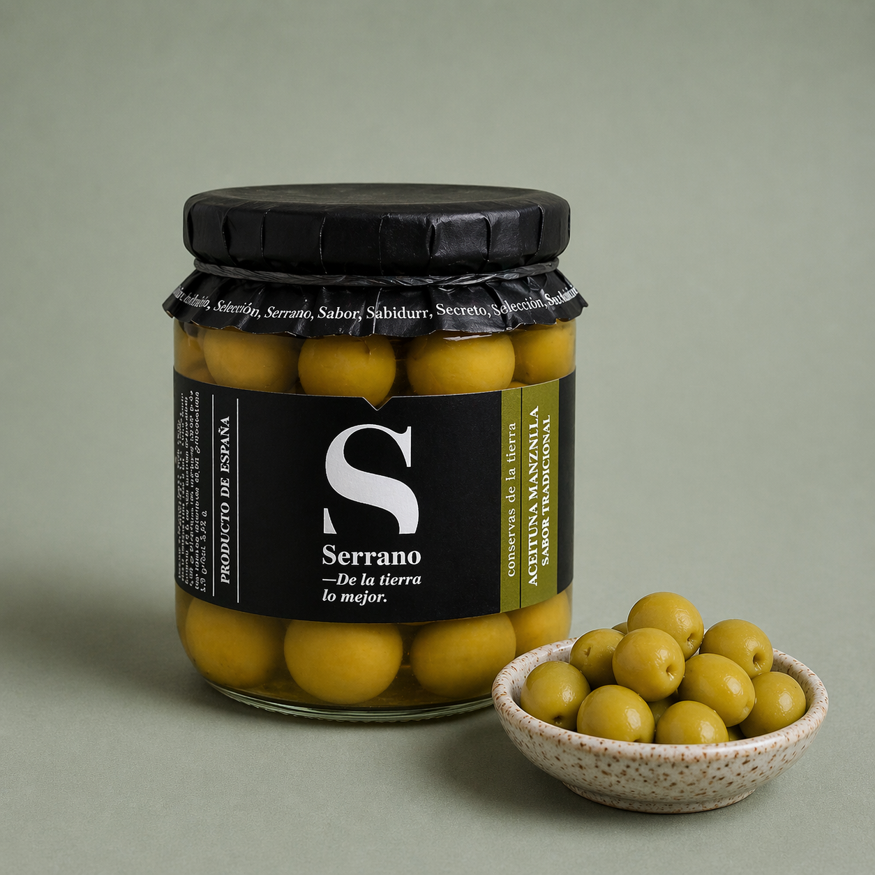 Tarro de aceituna manzanilla Serrano sabor tradicional con aceitunas en un cuenco.