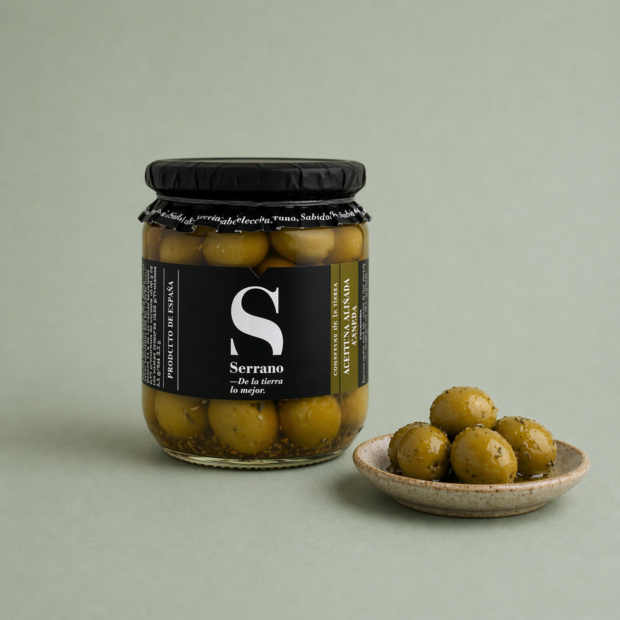 Tarro de aceituna verdial aliñada Serrano con especias y aceitunas servidas en un plato.