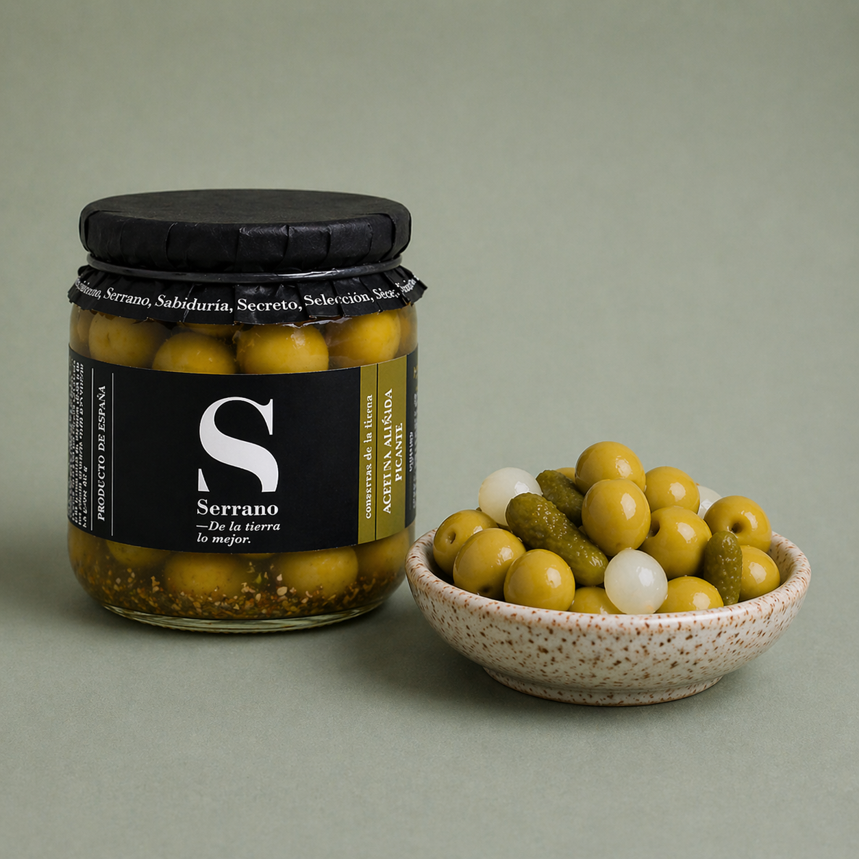 Tarro de cocktail de aceitunas sabor anchoa en vinagre Serrano con mezcla de aceitunas, pepinillos y encurtidos en bol.