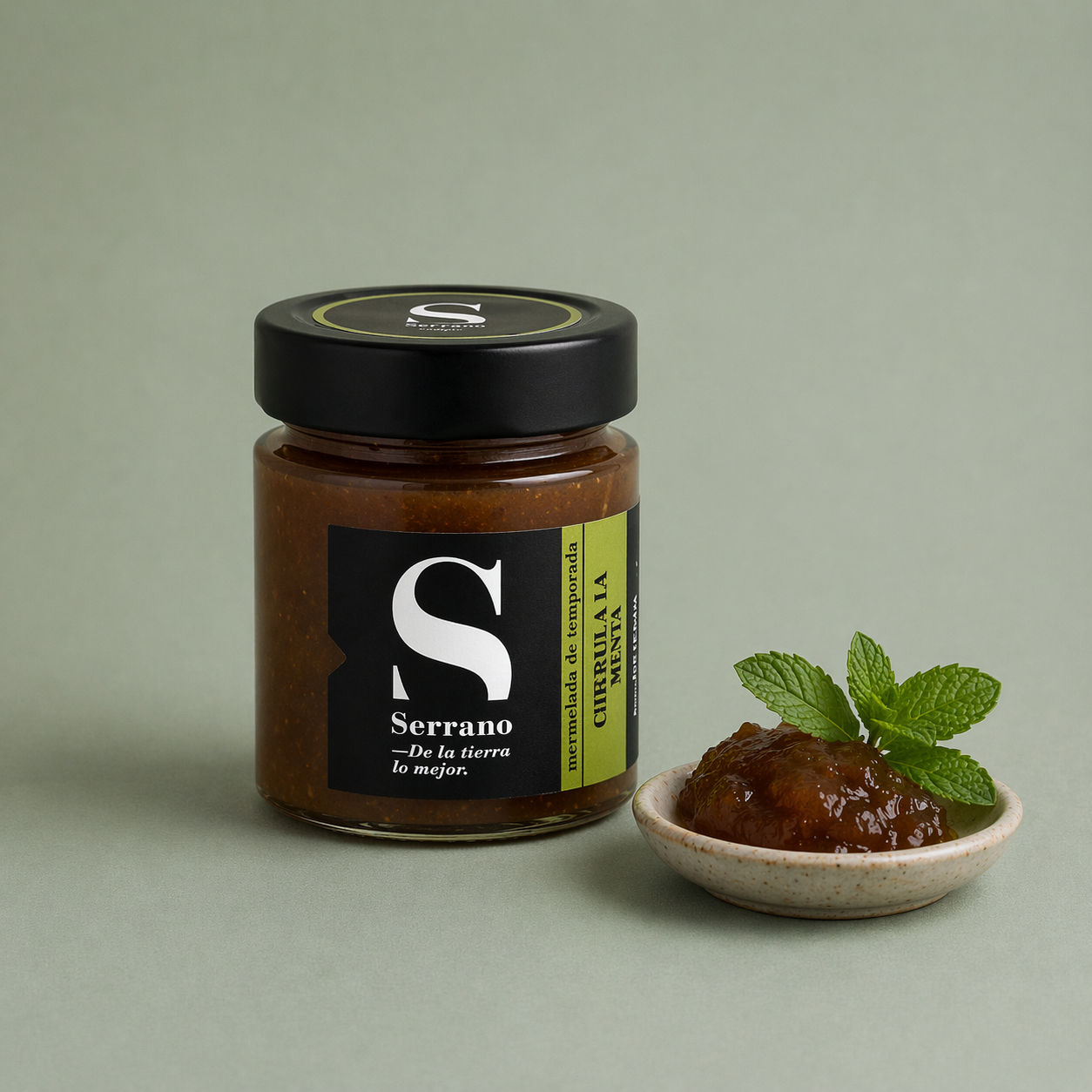 Tarro de mermelada de ciruela con menta Serrano con porción servida en un plato y hojas de menta fresca.