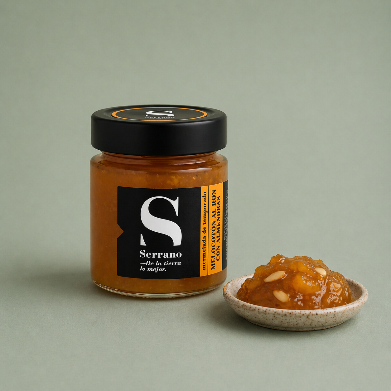 Tarro de mermelada de melocotón al ron con almendras Serrano con porción servida en un plato.