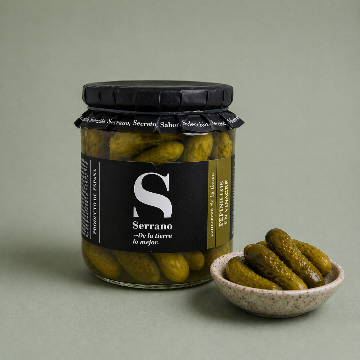 Tarro de pepinillos Serrano en vinagre con pepinillos en un cuenco.